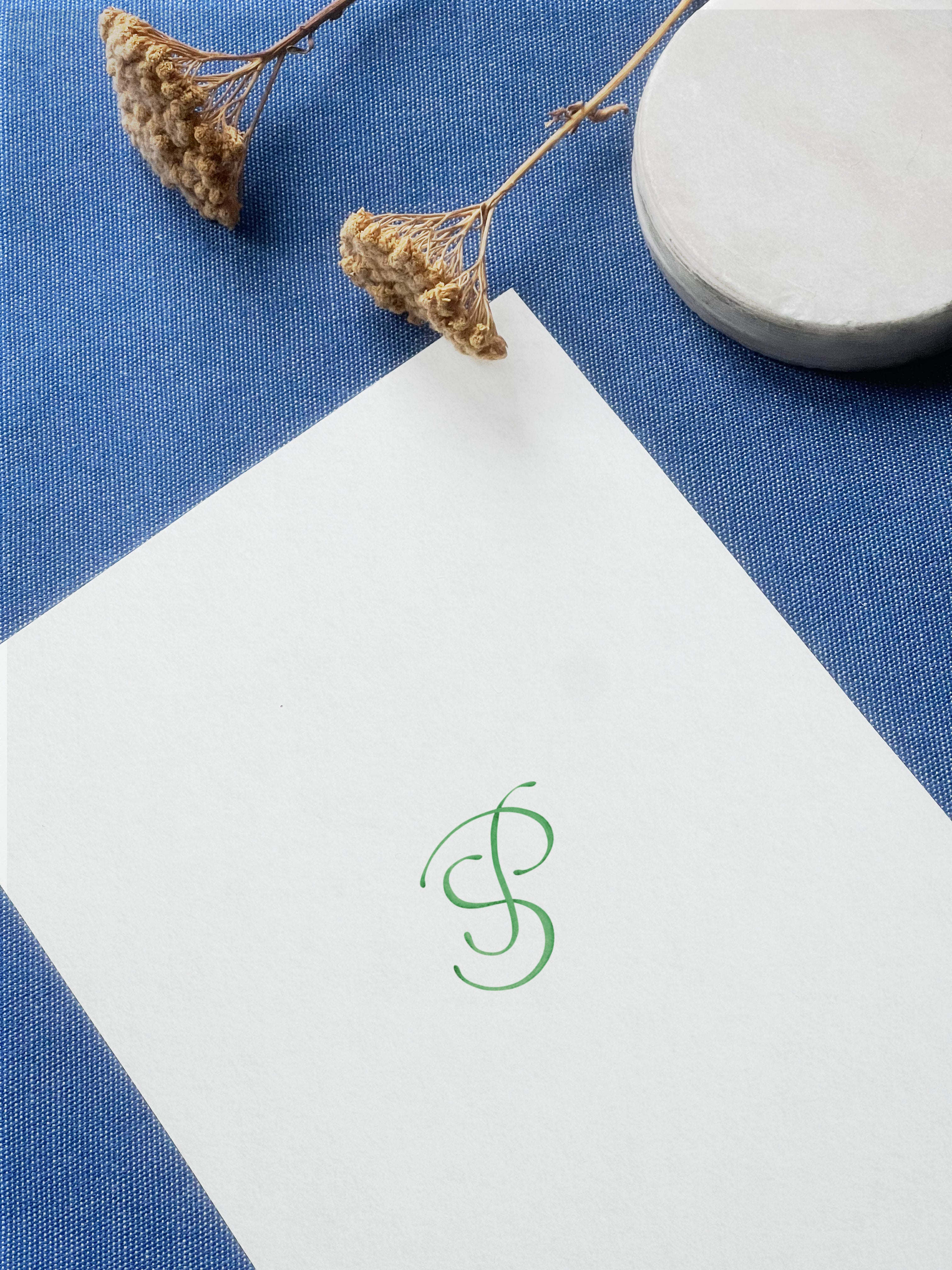 Watercolour wedding invitation with pastel green minimalistic Monogram, showcasing the artistic vision of the couple